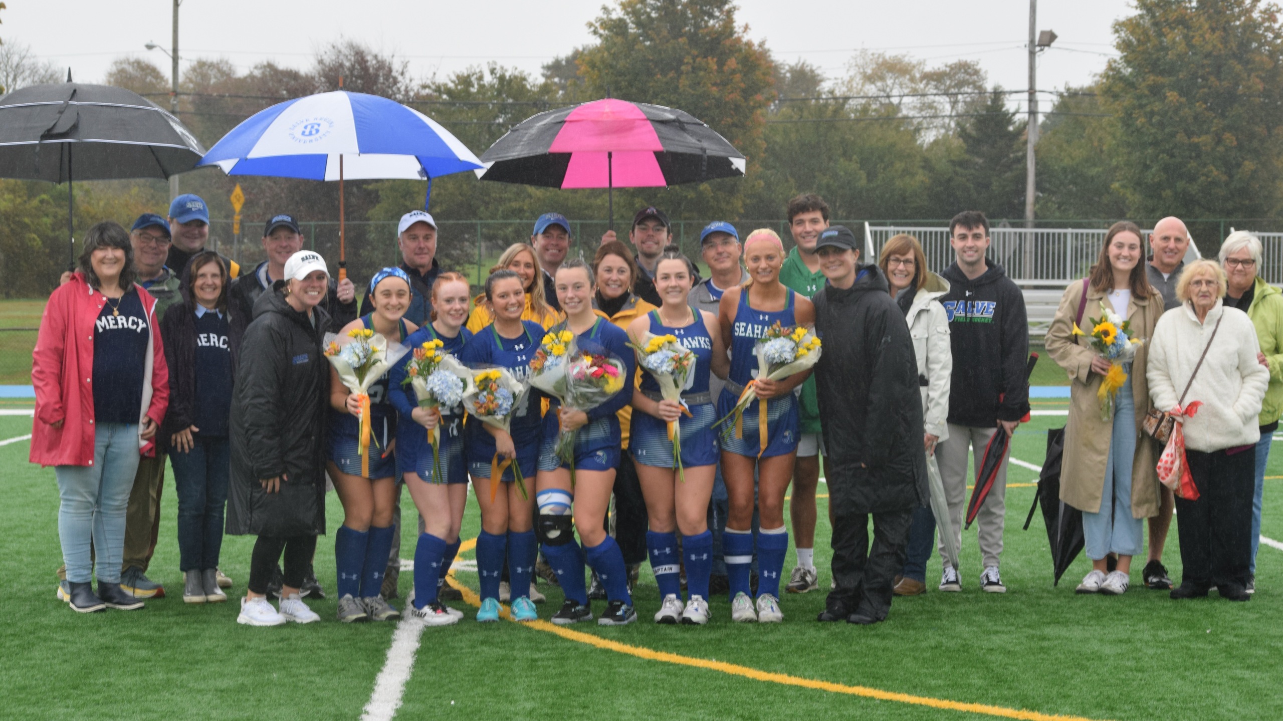 Class of 2024 - Elizabeth Clark, Lauren Foster, Lily Tordone, Maeve Ledwith, Ashley Lefebvre, Shannon Kennedy - Salve Regina field hockey seniors joined by their families and coaching staff during pre-game recognition.