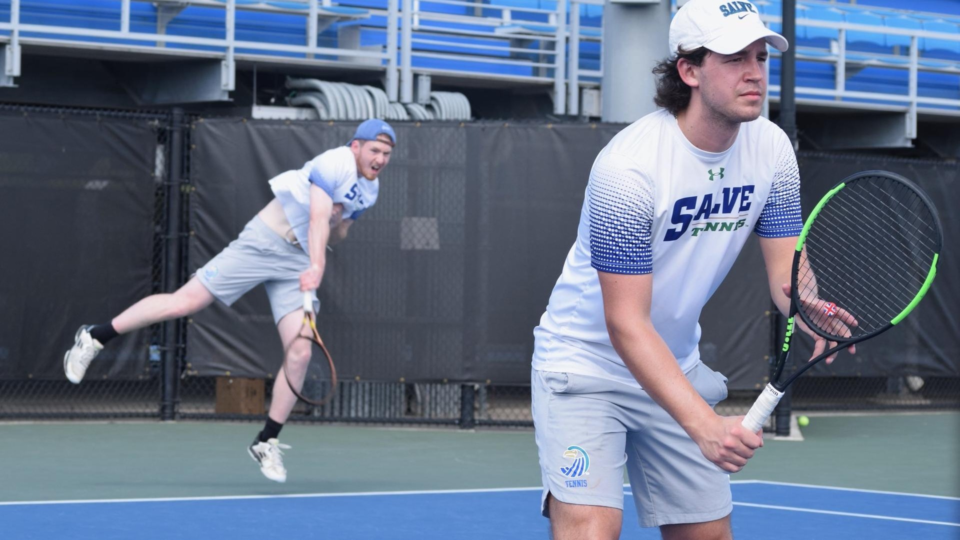 Jacob Faulise (serving in background) and Ned Batstone competed with different partners against the Lyons. (Photo by Ed Habershaw '03M)