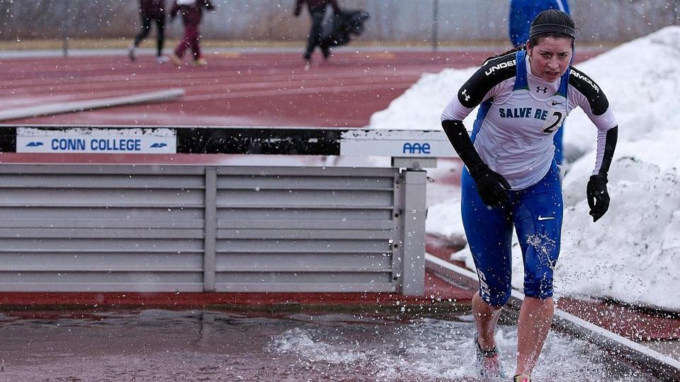 Sophomore Sam Gisonni deals with the weather and steeplechase elements during women's track and field competition at the U.S. Coast Guard Academy and Connecticut College. (Photo by Jen McGuinness)